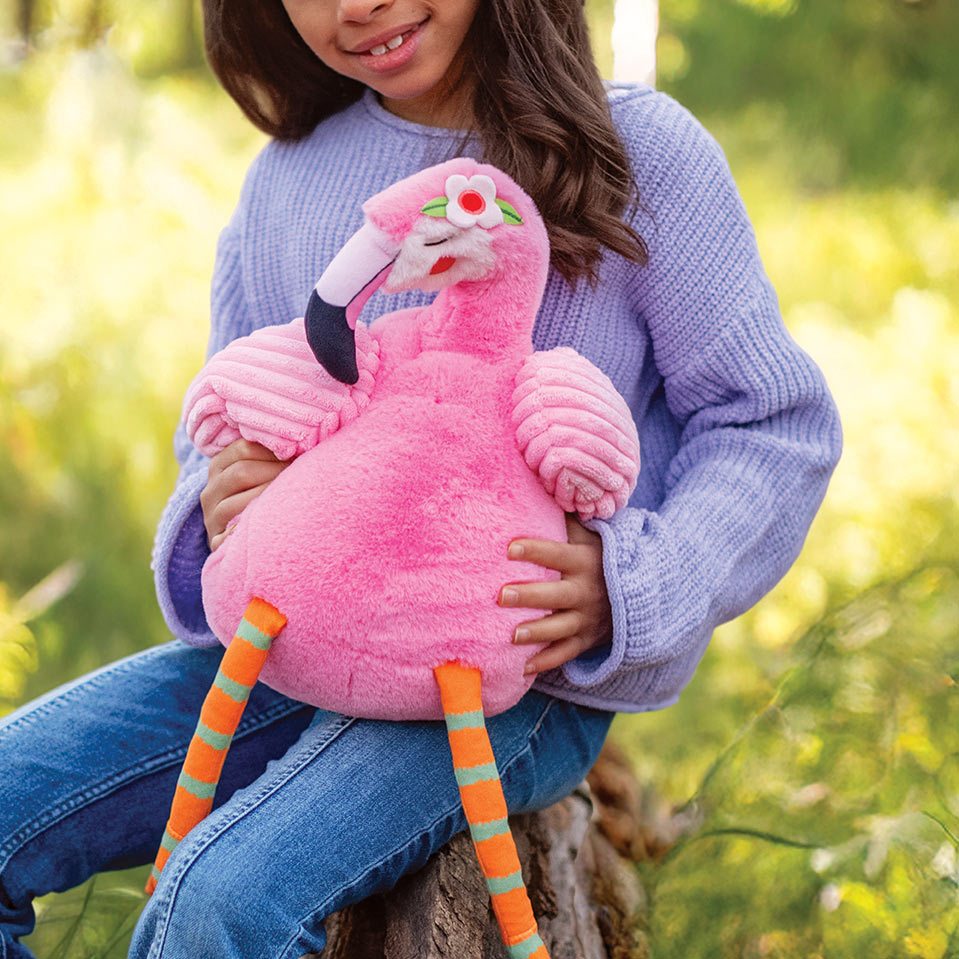Child holding a pink plush flamingo toy outdoors