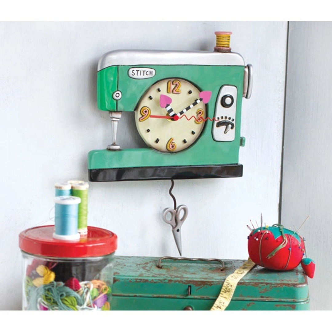 Sewing machine-themed clock on a white wall with sewing accessories below.